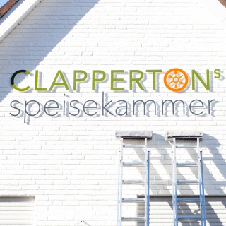 Aufängung Beschriftung Clappertons Speisekammer Fassade, Männer bringen die Buchstaben an: Clappertons Speisekammer entsteht